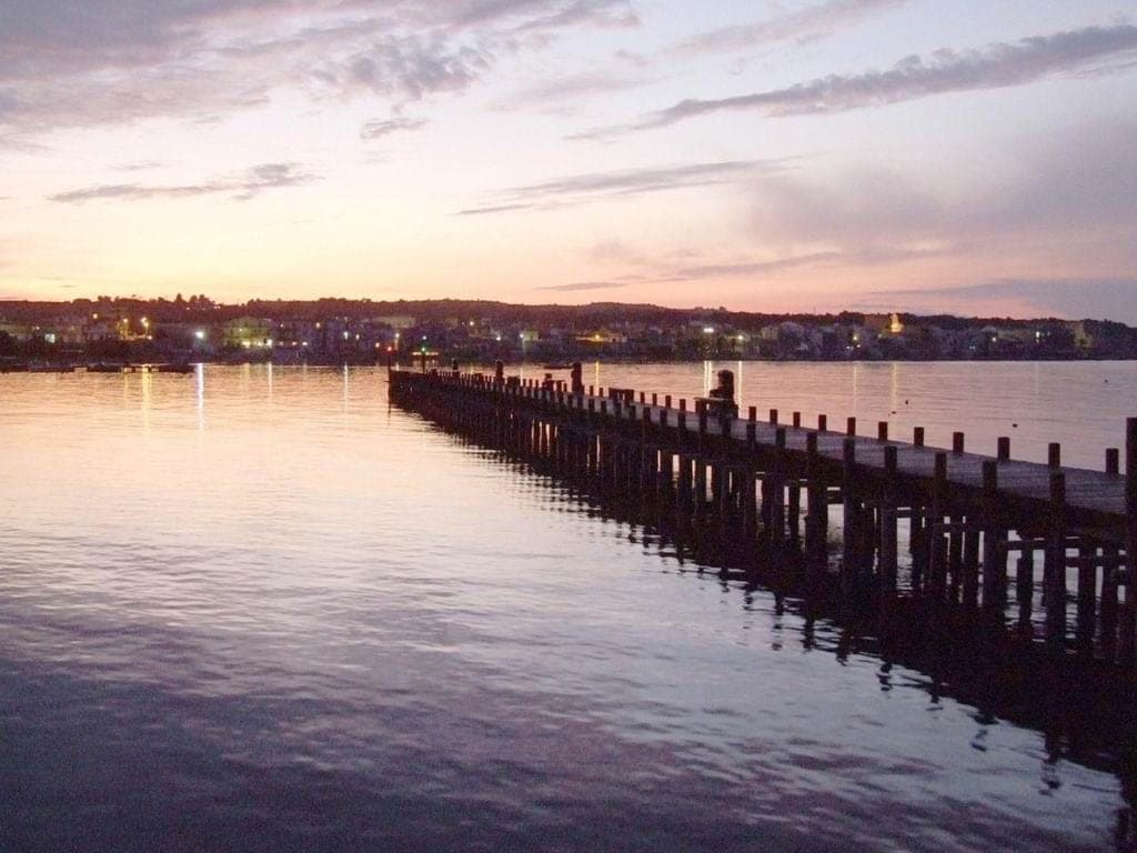 A long wooden pier stretching across calm water at dusk