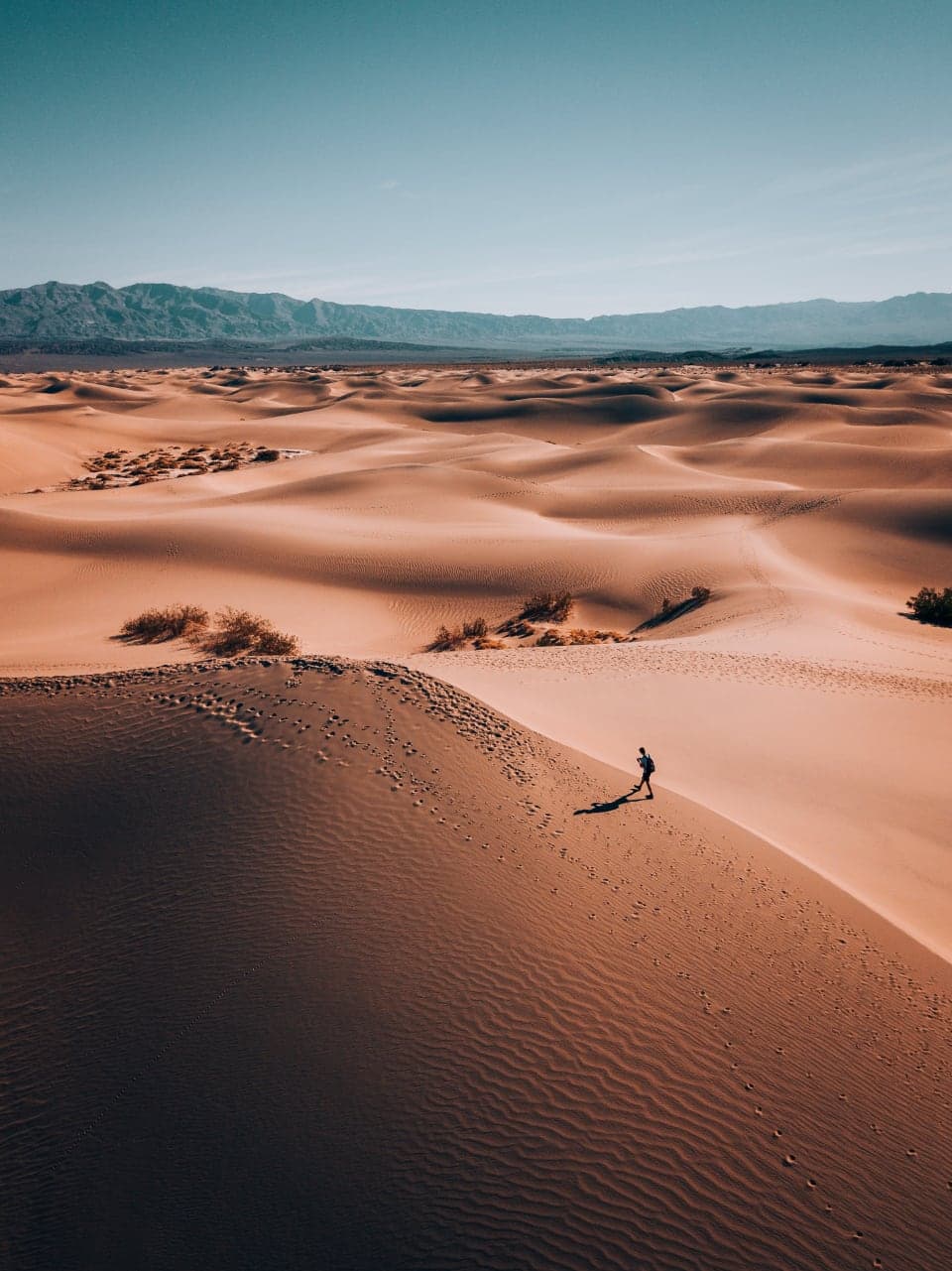 Aerial view of a walker crossing warm sand dunes
